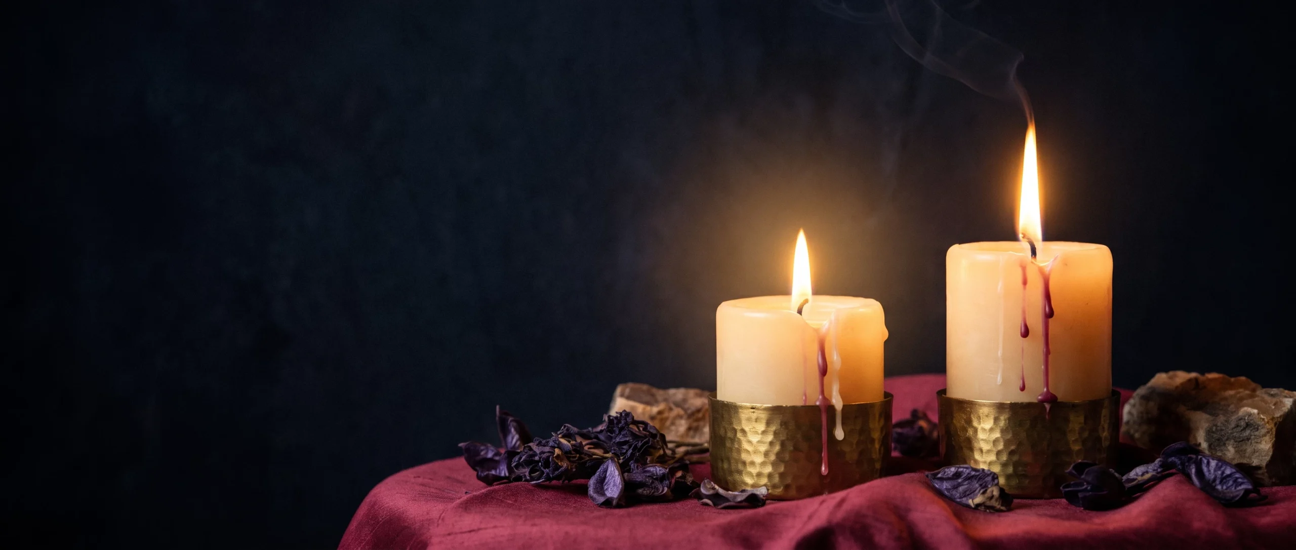 Two candle flames against black — one steady, one wavering — their light merging in the middle.